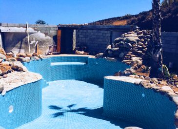Swimming pool with built-in rock feature, created by Almeria Builders